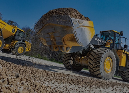 The word “aggregates” is on top of a John Deere 944 X-Tier Wheel Loader and 460 P-Tier Articulated Dump Truck working at a gravel site. 
