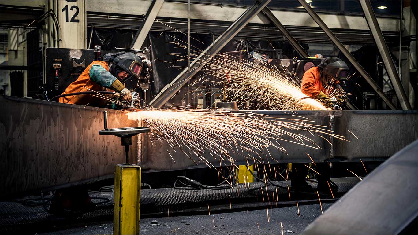 Sparks fly while John Deere welders work on an excavator