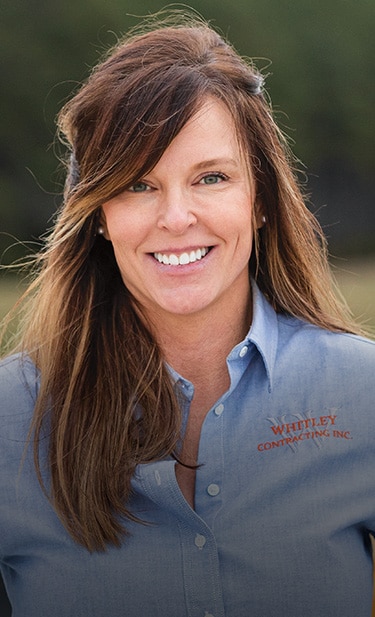 Brandy Whiley is standing at a job site looking toward the camera.