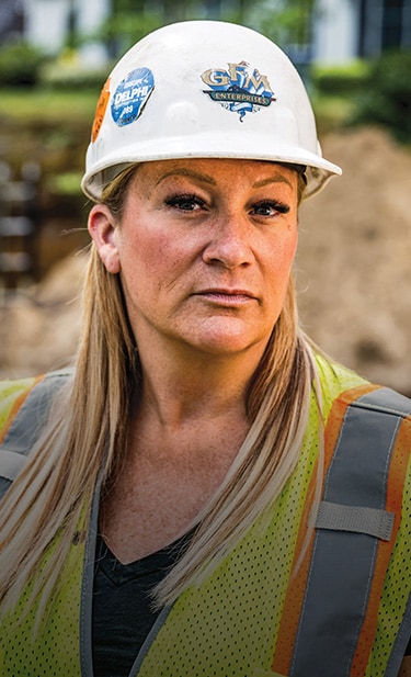 Jennifer Morris is standing at a job site looking toward the camera.