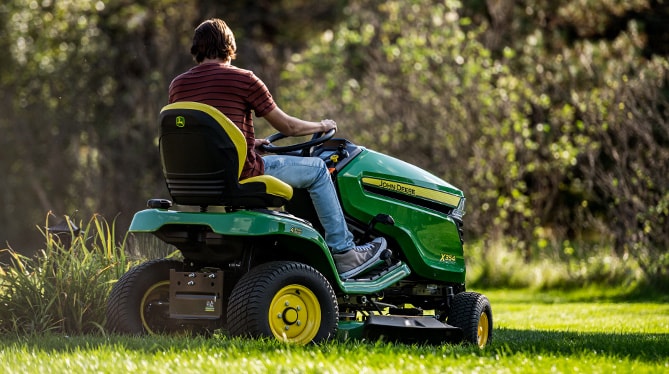 A person riding on a ztrak mower mowing the grass