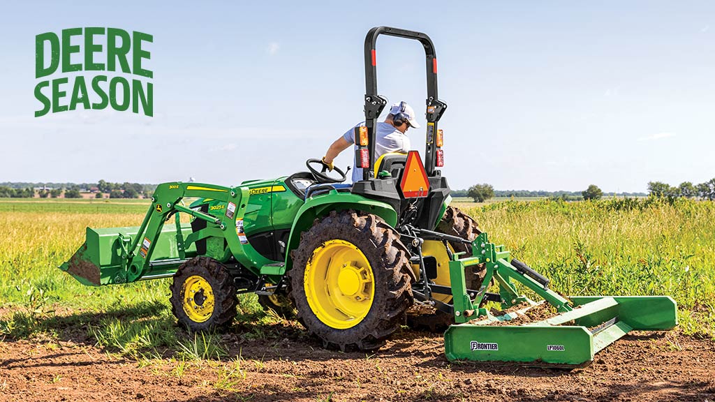 Farmer driving a 3 Series Compact Tractor with logs in its bucket.