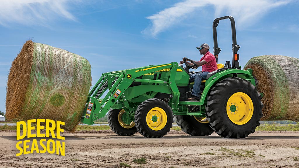 person on a tractor picking up a hay bale