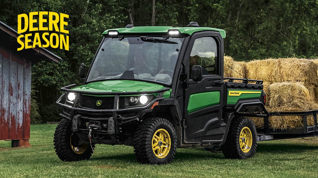 Person driving a Gator Utility Vehicle across a dusty field.
