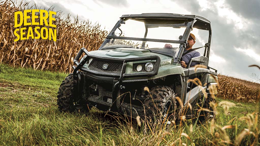 Person driving a Gator Utility Vehicle with corn in the background
