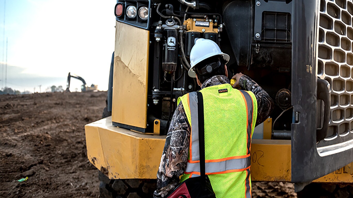 Equipment operator looking at a John Deere industrial engine in a John Deere piece of equipment 