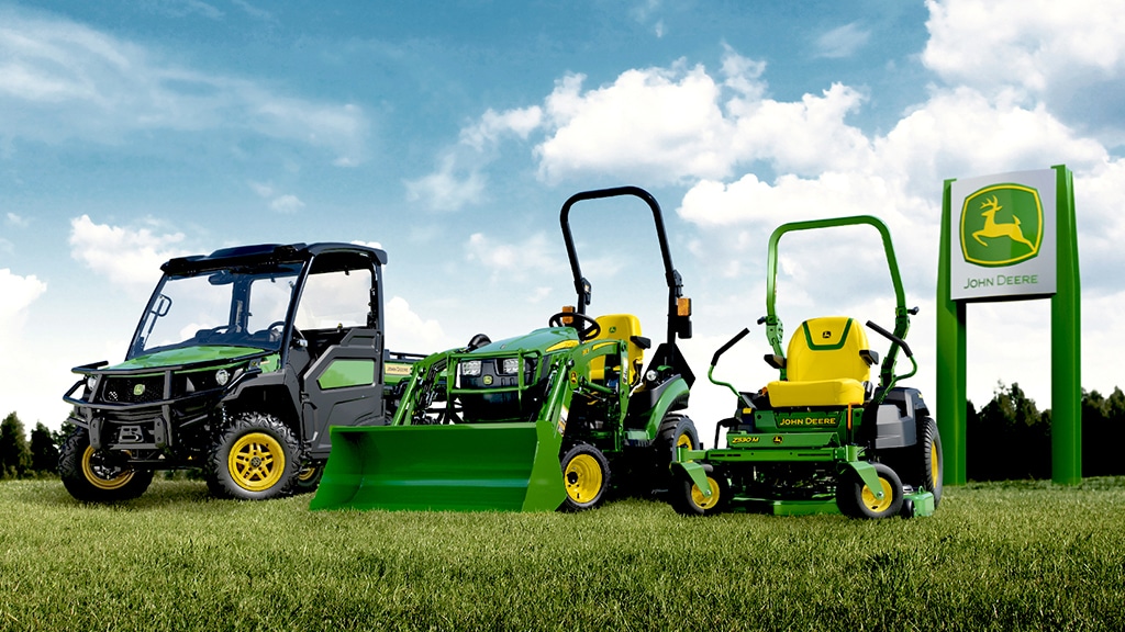 Lineup of a Gator™ UTV, compact tractor, and Zero-Turn Lawnmower in front of a John Deere sign.