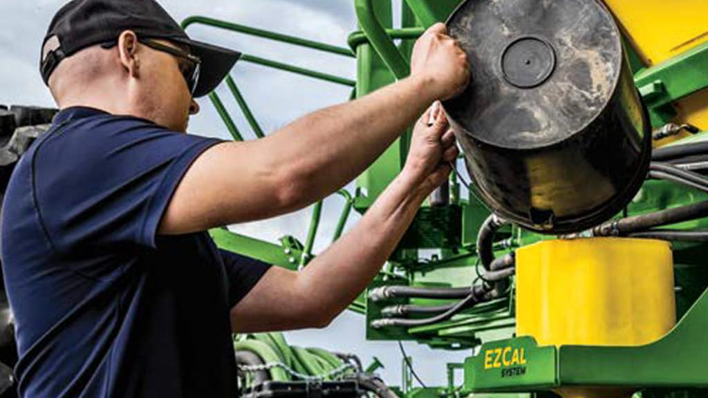 Photo of a farmer pouring seeds into the EZCal measurement system.