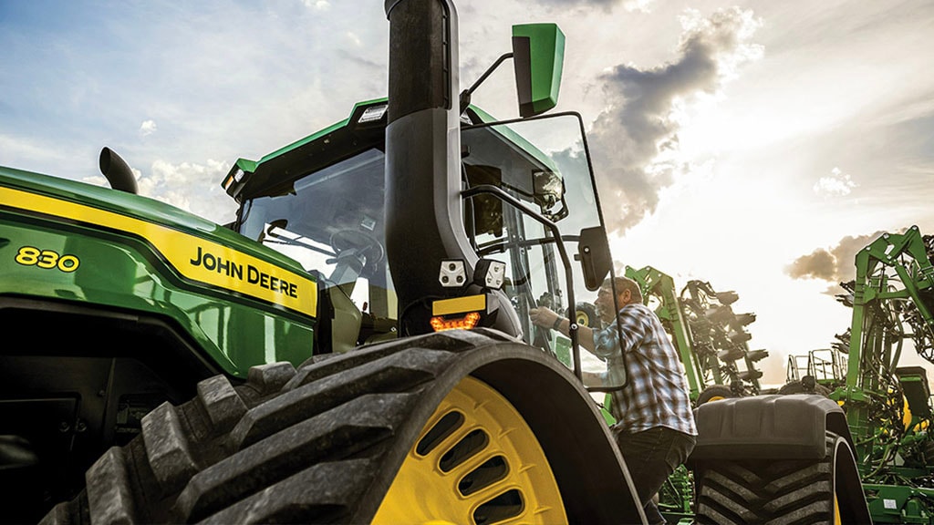 Exterior of a farmer climbing into a John&nbsp;Deere 9RX tractor.