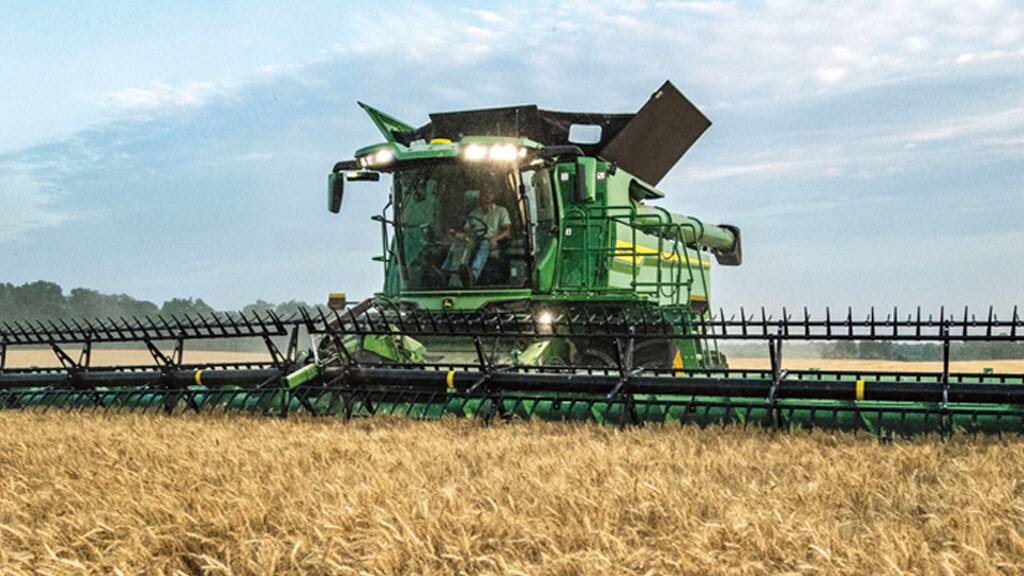Photo of the front of a John&nbsp;Deere S7 Combine harvesting wheat with a draper head.