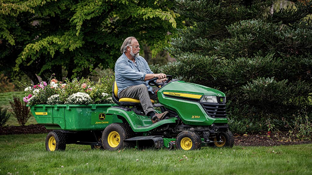 Person pulling a bed of flowers in a 17P cart on a X350 lawn tractor.