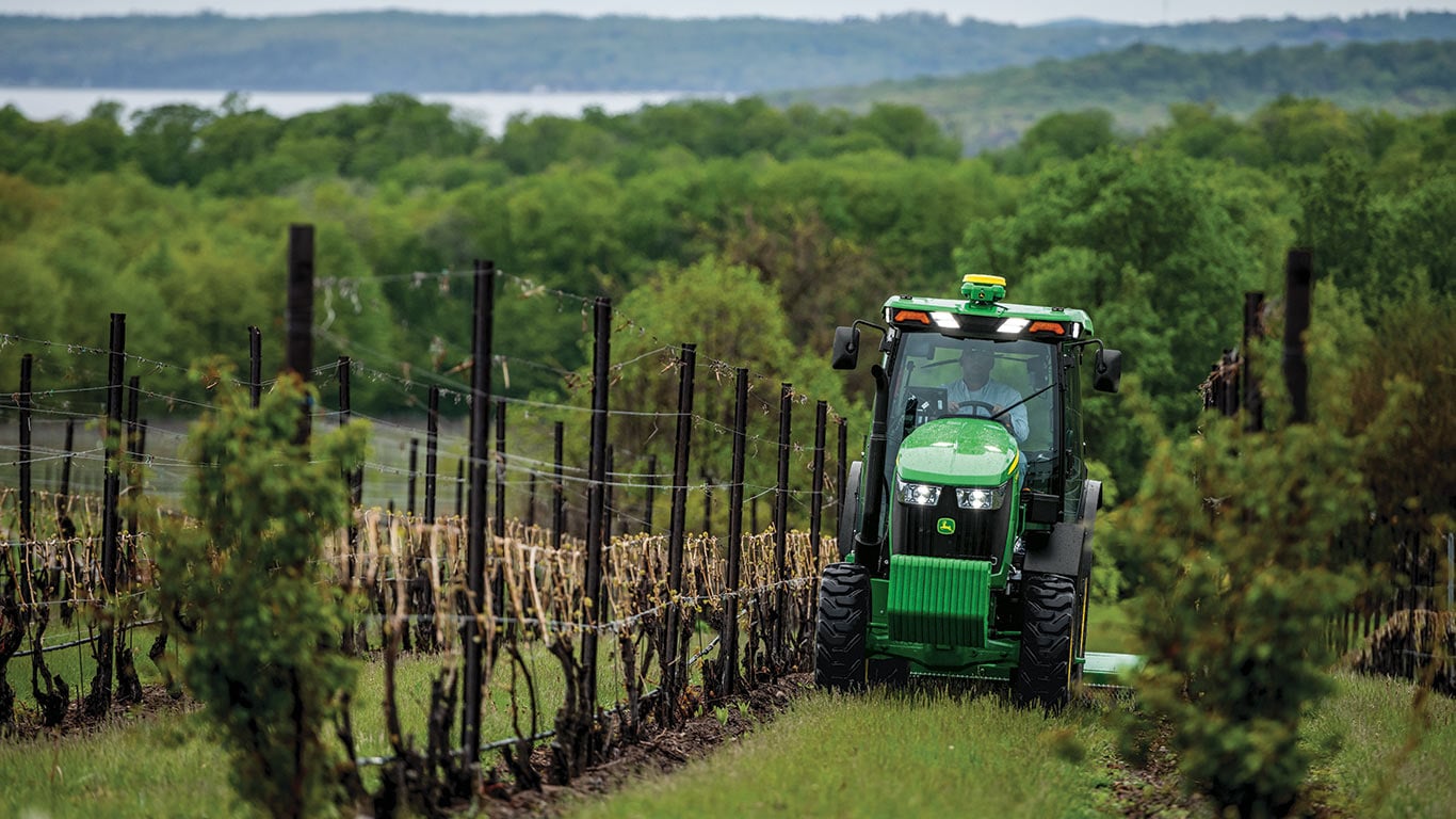 John Deere tractor moving through a vineyard