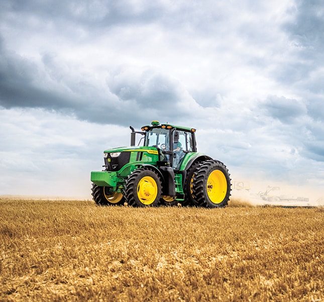 A green tractor in a field on a cloudy day.