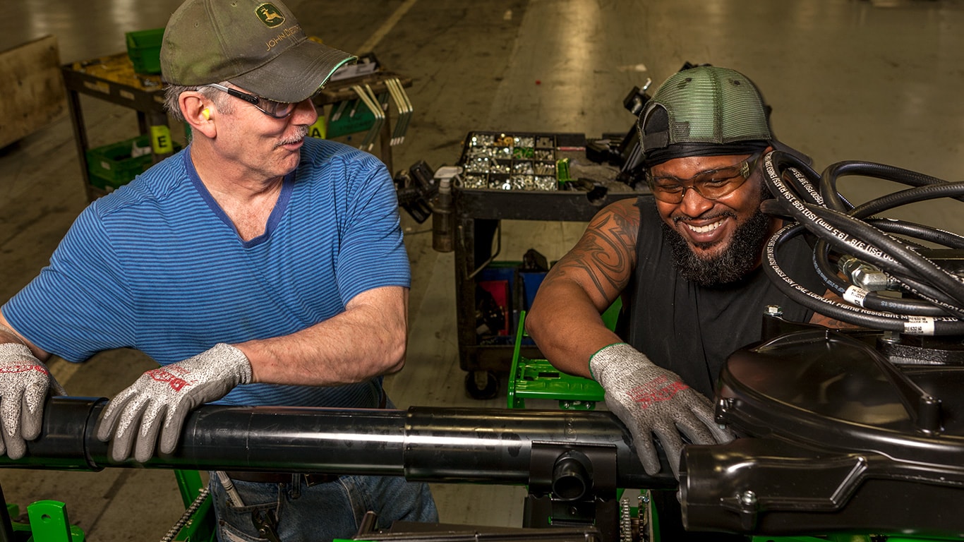 Two workers share a smile while working on the factory floor