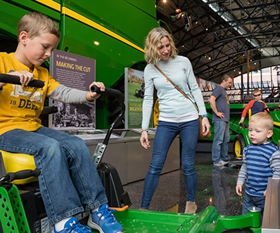 Mother and father with their children looking at John Deere Lawn and Garden equipment