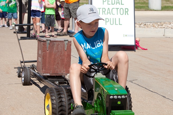 Young boy riding a John Deere pedal tractor in the pedal-powered tractor pull activity