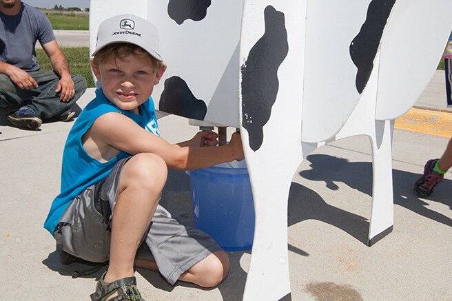 Young boy milking a fake cow