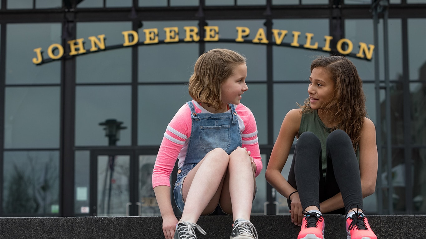 Two girls talking outside of the John Deere Pavilion