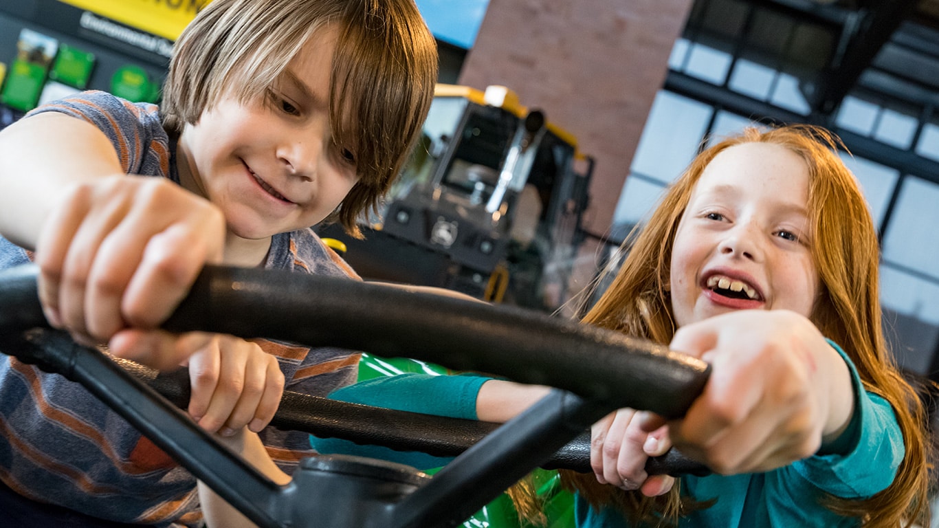 Kids playing on a tractor inside the John Deere Pavilion