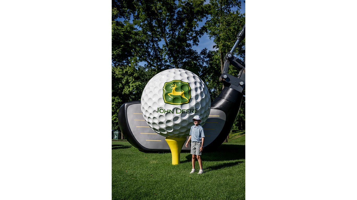 child standing near giant golf ball