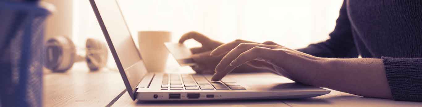 Woman using a computer with credit card in hand