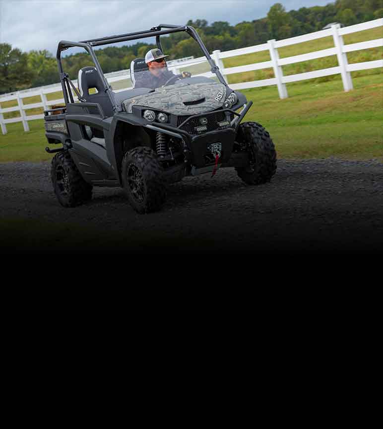 Man driving a camoflauge Gator Utility Vehicle on a gravel driveway