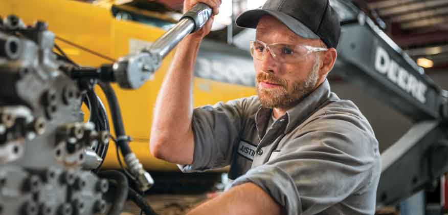 Man with tools working on John Deere Compact Construction Equipment