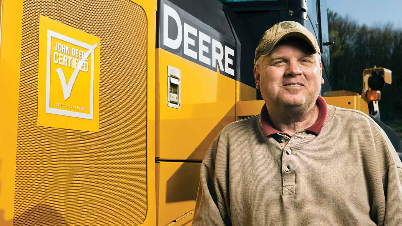 Man standing next to John Deere Construction equipment