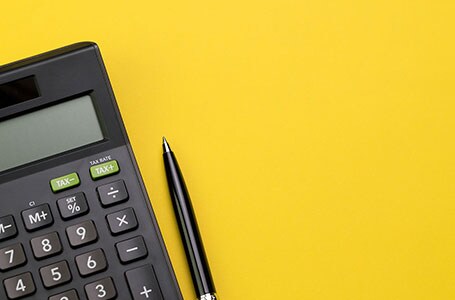Calculator and pen on yellow background
