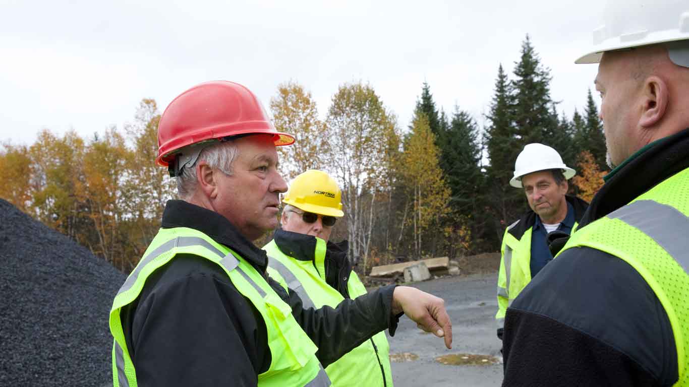 Four men in construction gear at a construction site talking