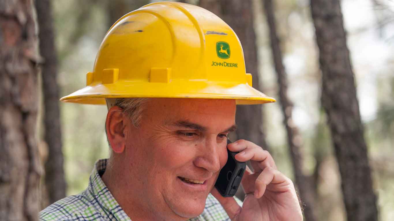 Man with John Deere hardhat talking on his cell phone