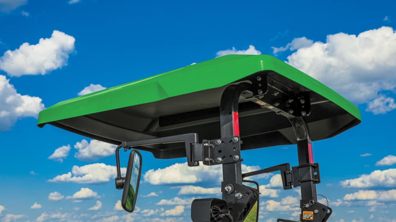 green utility tractor canopy with blue sky and clouds behind