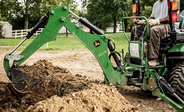 Man using backhoe on compact utility tractor