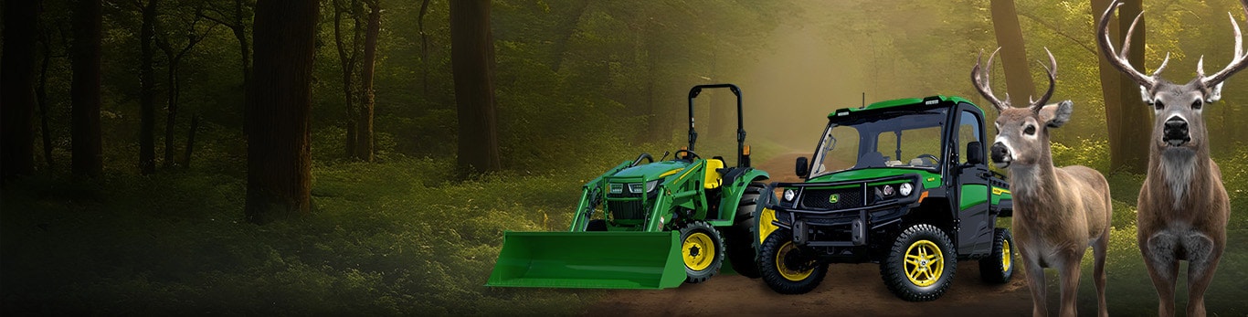 Bucks in front of gator and lawn tractor in a forest
