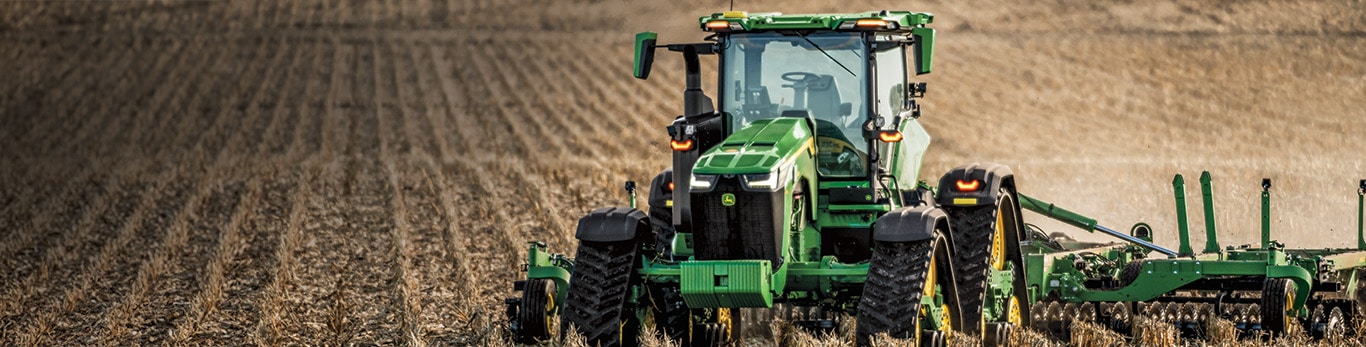 Row-crop tractor tilling a field autonomously.