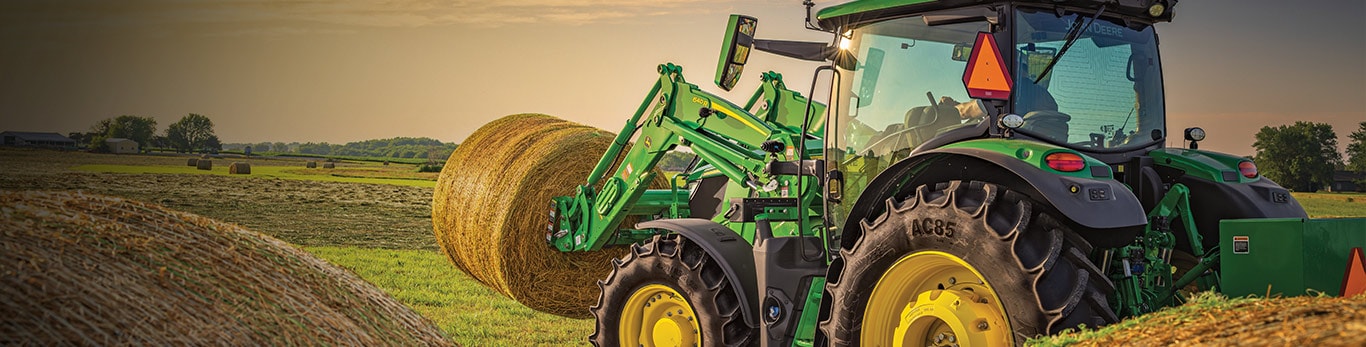 6 Series Tractor baling hay during a sunset