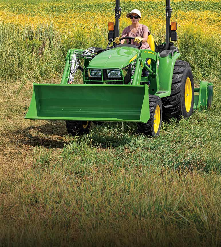 Woman driving a 3E Series Compact Tractor in a field.