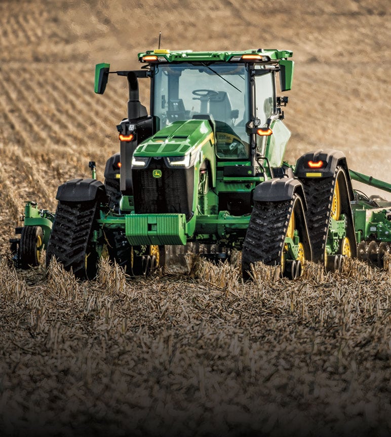 Row-crop tractor tilling a field autonomously.