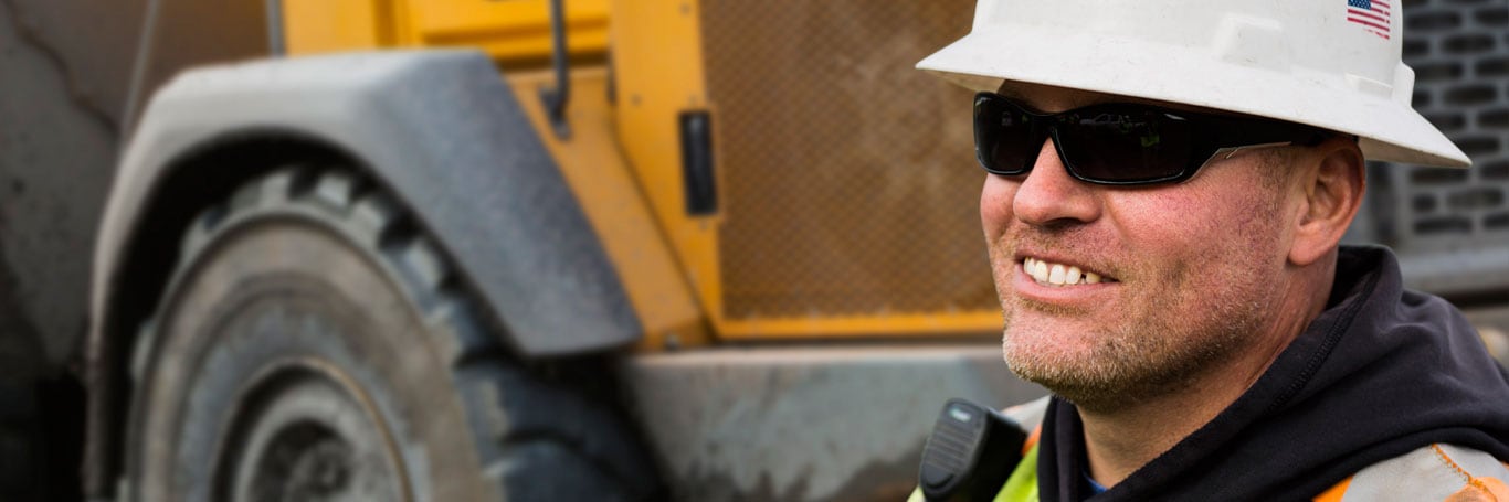 Construction worker stands with John Deere construction equipment in the background