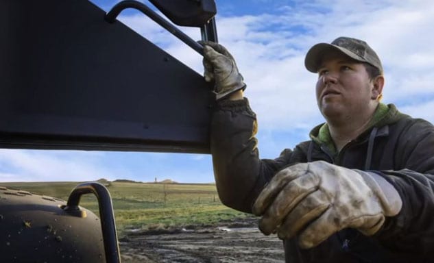 Farmer climbing into cab of farm equipment.