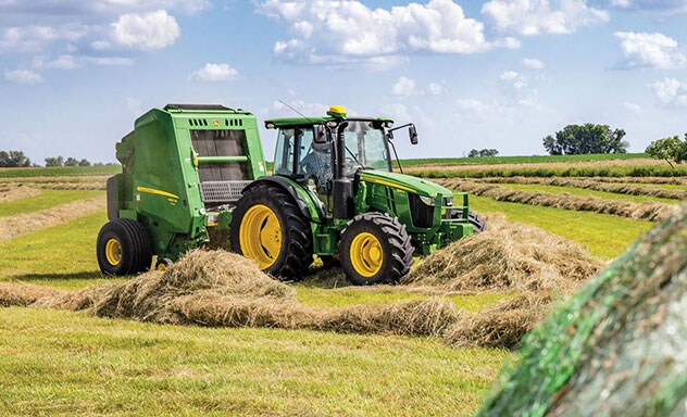 Tractor and baler in field baling hay