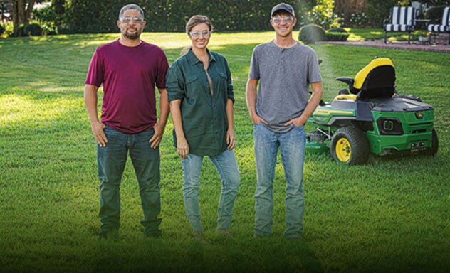 Three people in a residential yard in front of an electric mower