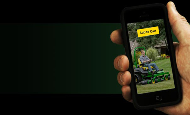 Hand holding mobile phone which displays a man riding lawn mower with Add to Cart button on screen.