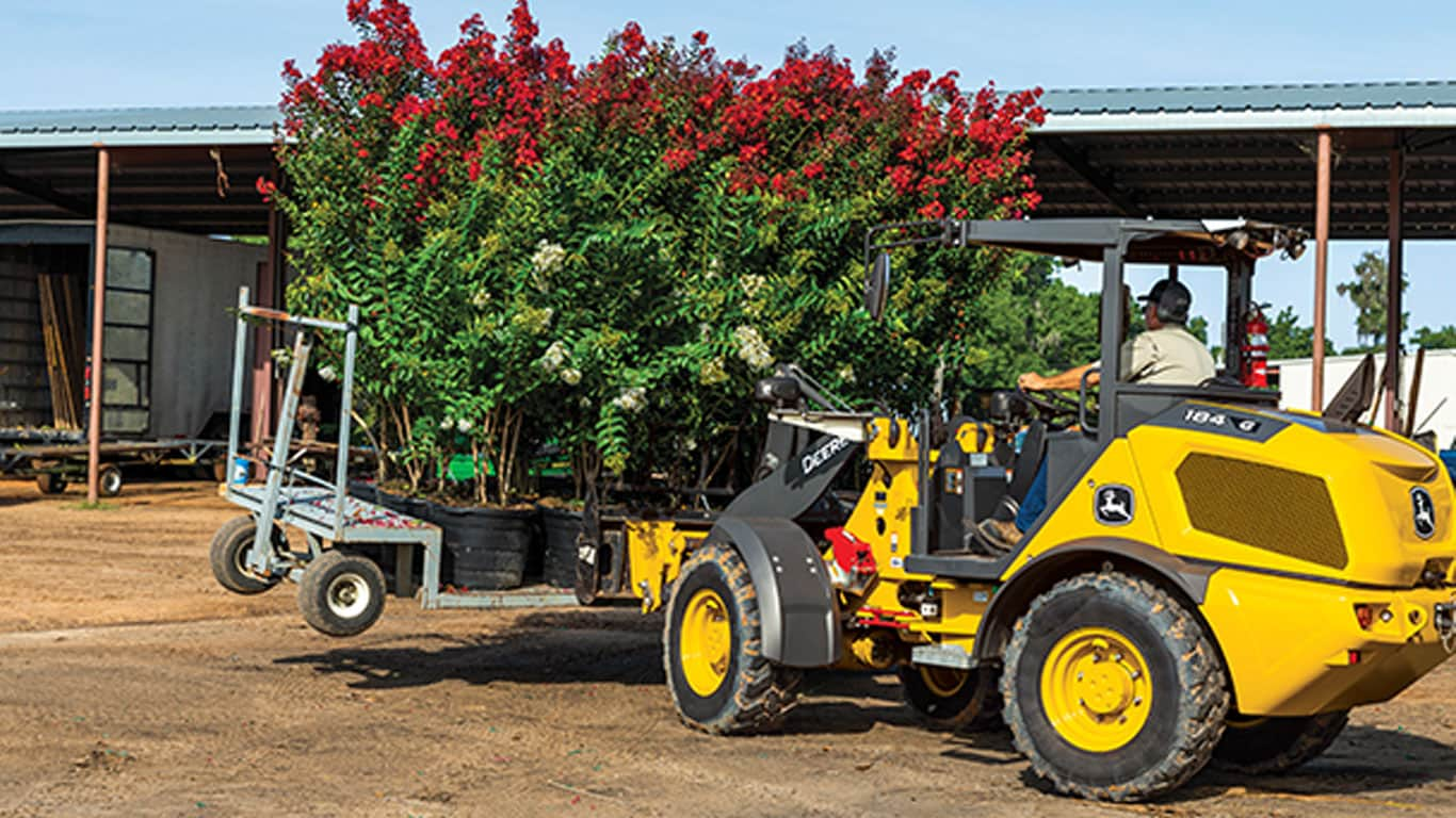 Skid steer moving a pallet of plants