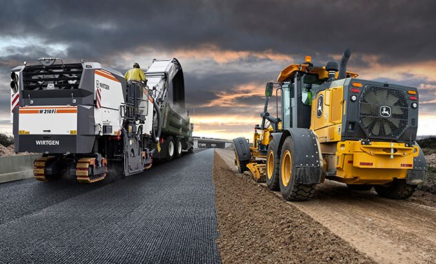 Wirtgen and John Deere roadbuilding machinery working on road side by side.