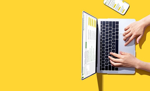 Overhead view of hands typing on laptop with mobile phone nearby on yellow table