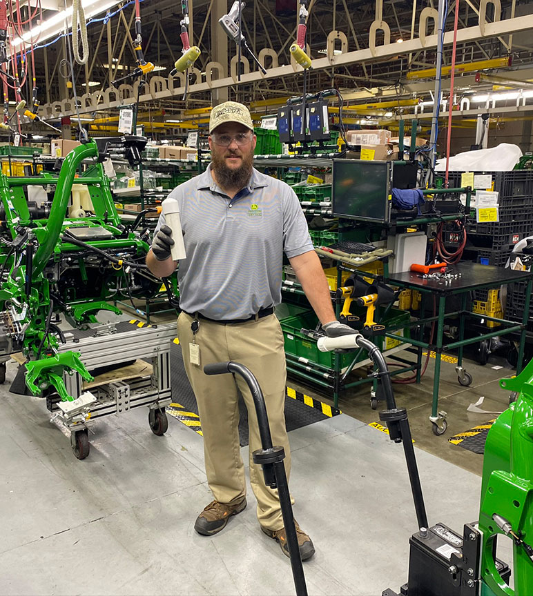 Jason Sherron, assembly manufacturing engineer, holds PUSH protective handles made from PVC pipe to fit over assembly cart handles.
