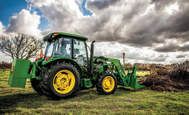 John Deere 5075E Utility Tractor doing grapple work on a cloudy day