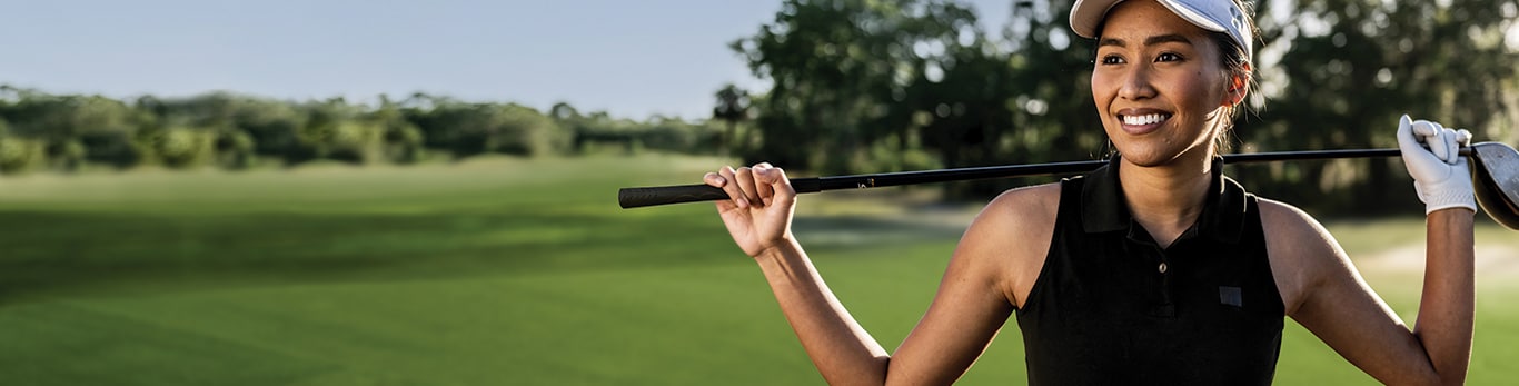 Smiling golfer holding golf club over their shoulders.