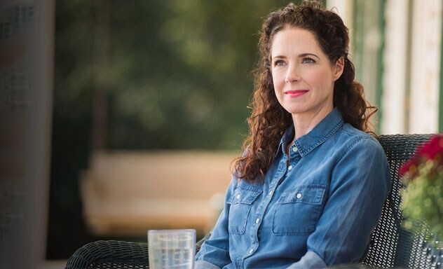 Woman sitting in a wicker chair on a porch